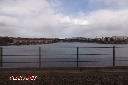 Stockholm: pohled z tramvaje Tvärbana na záliv Essingffjärden, po mostě v pozadí vede kromě silnice i zelená trať metra, 14.04.2021 © Jan Přikryl